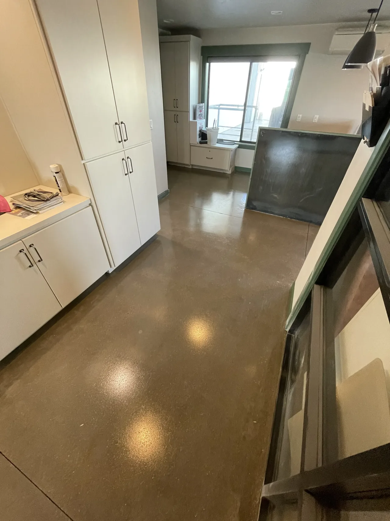 Brown-toned concrete floor beside built-in white cabinets