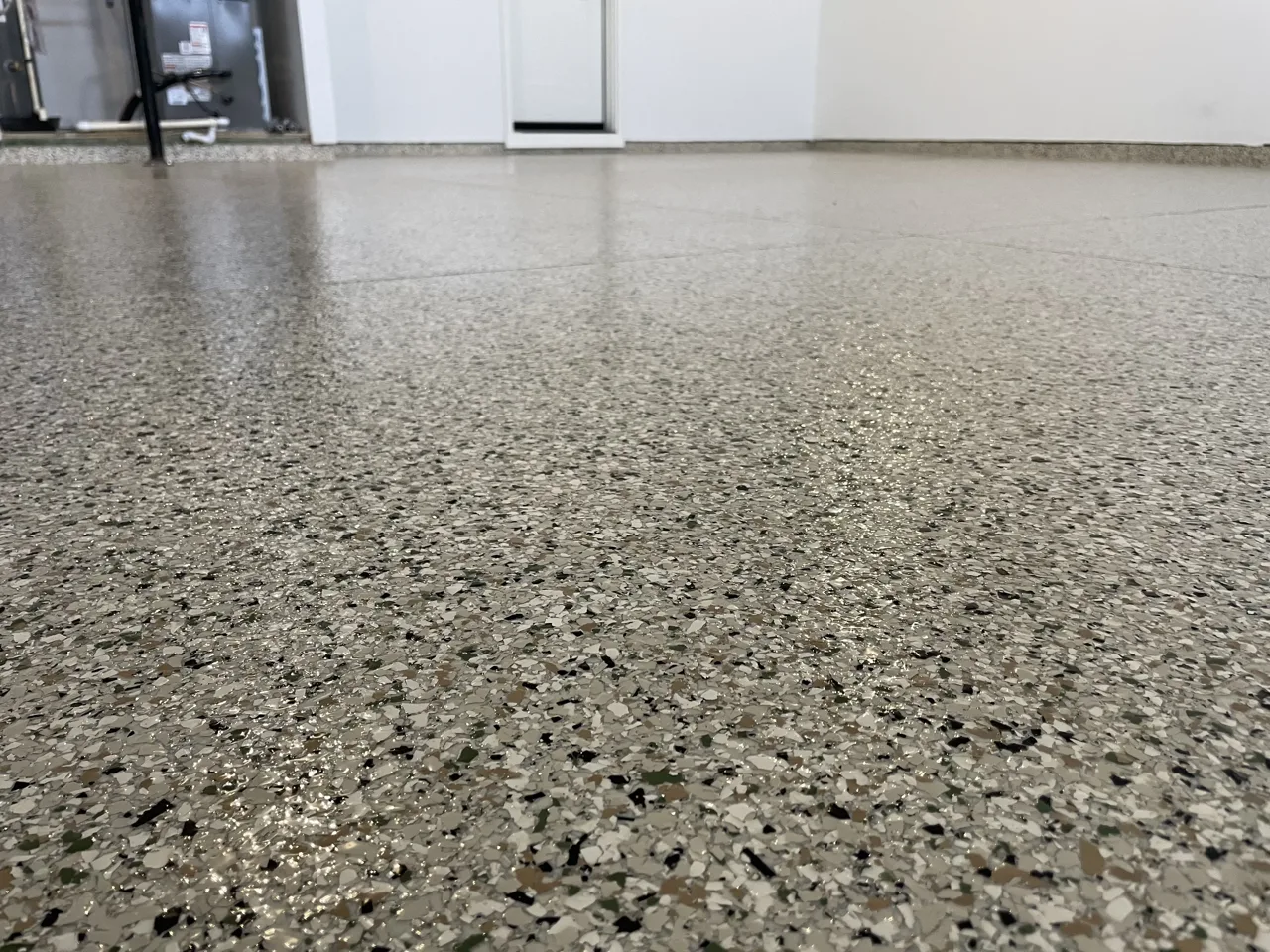 Close view of gray flake flooring beneath a white garage wall