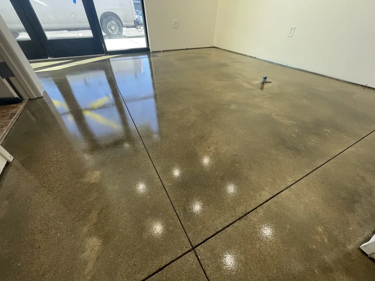Mottled brown concrete floor beside a glass entrance