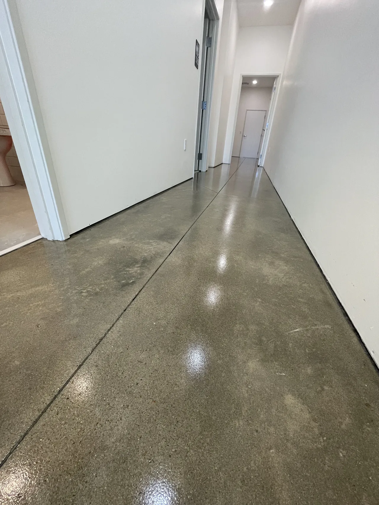 Mottled concrete floor in a white-walled hallway
