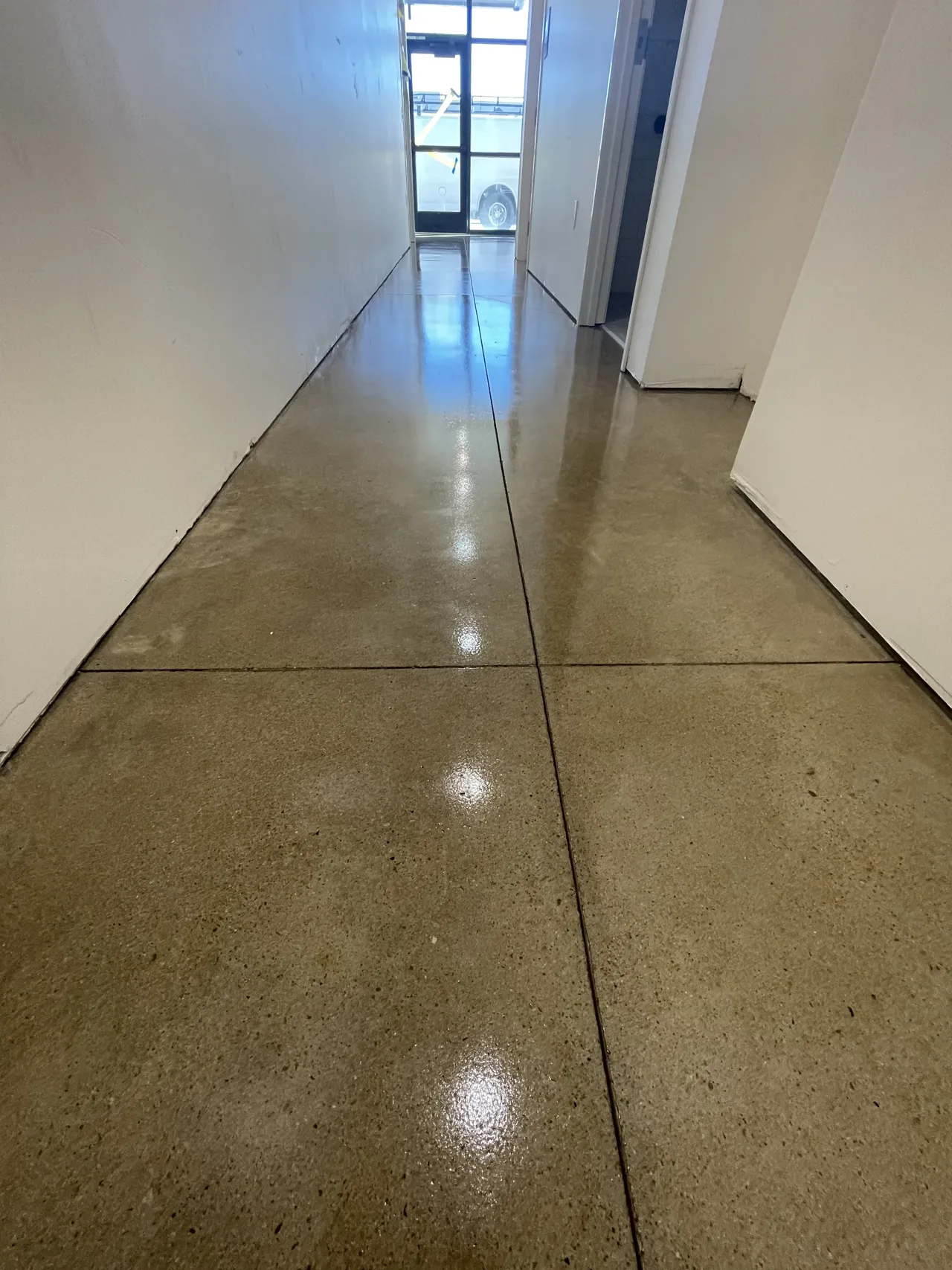 Reflective brown-toned concrete floor in a long hallway
