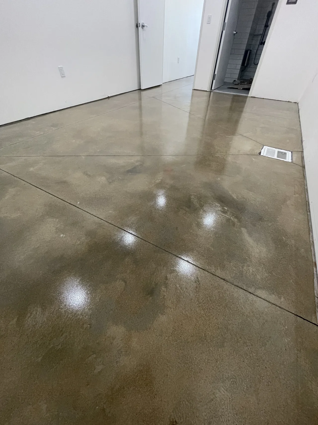 Reflective brown-toned concrete floor beside an interior doorway