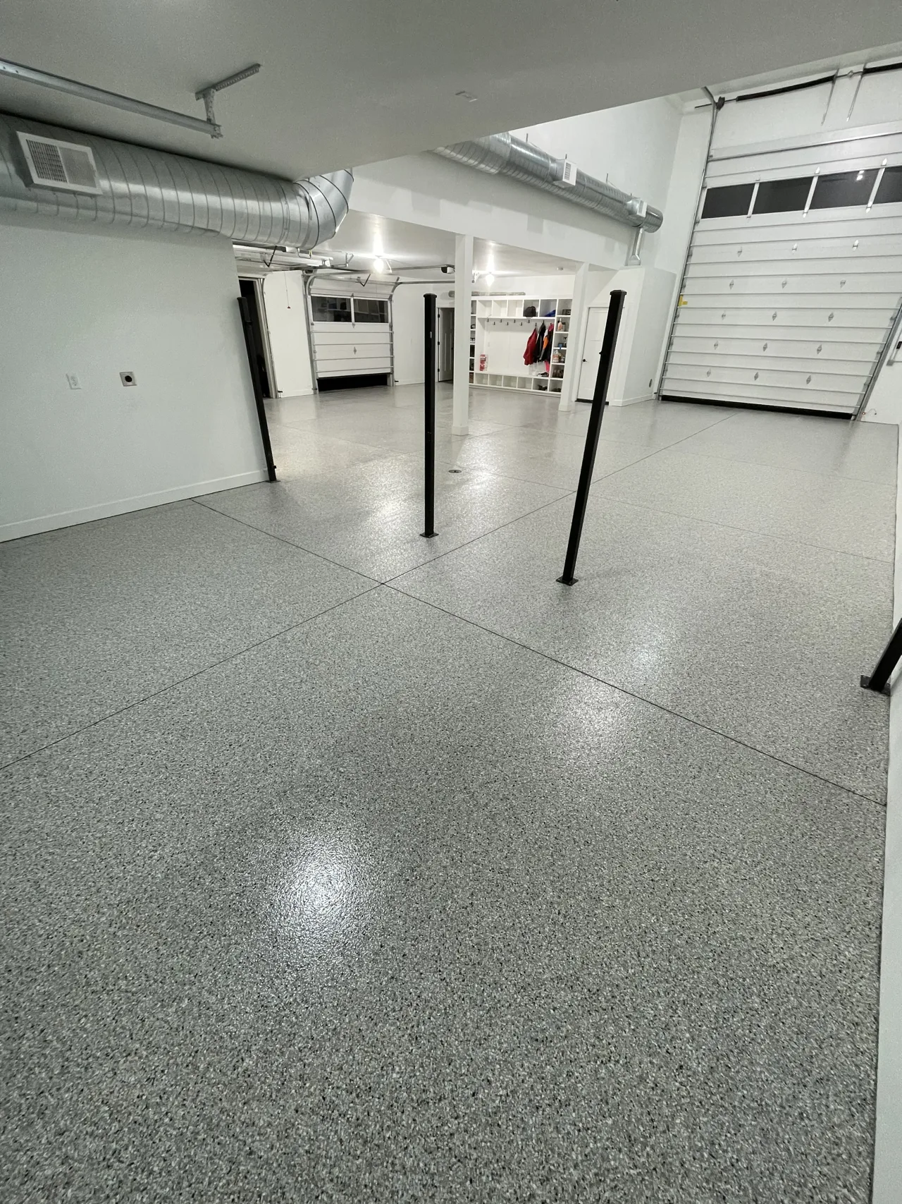 Gray flake garage floor with visible joints and black support posts