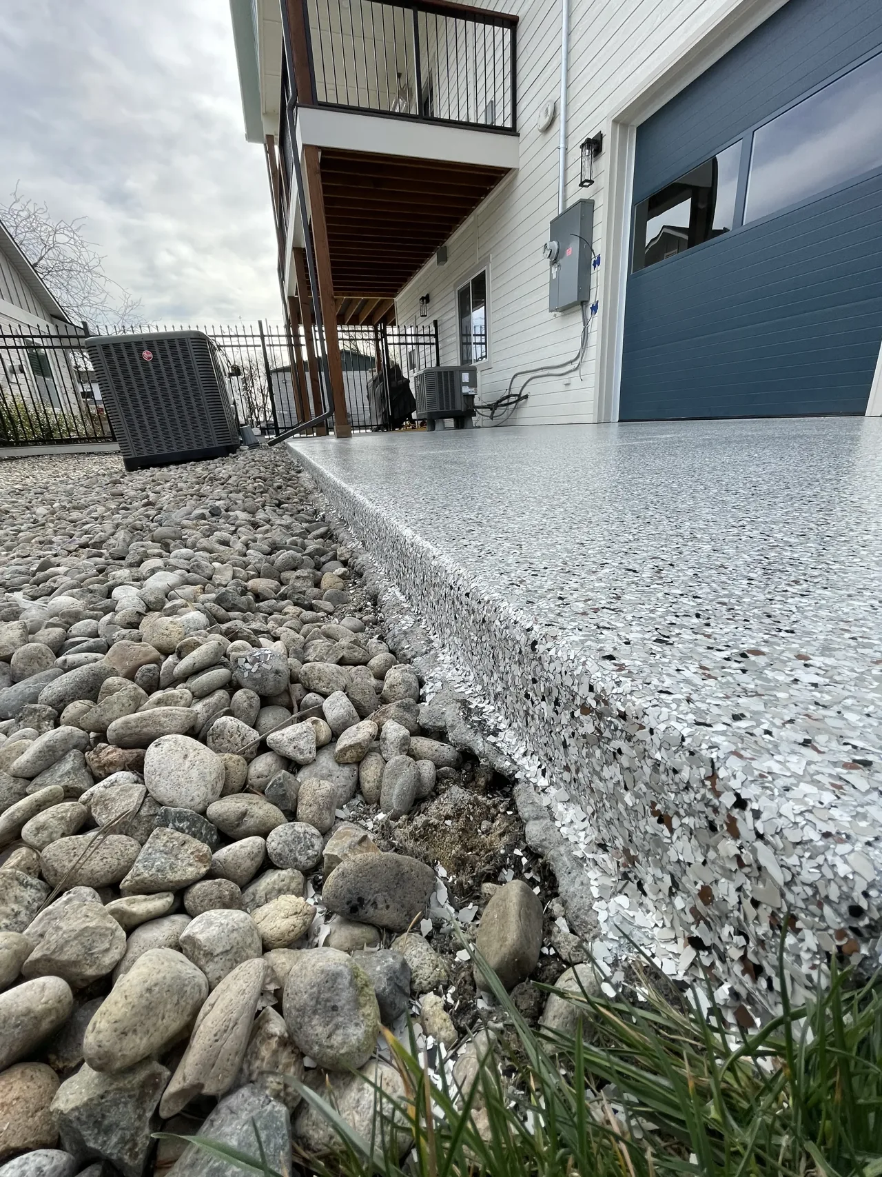 Gray decorative coating on an exterior landing beside a blue garage door