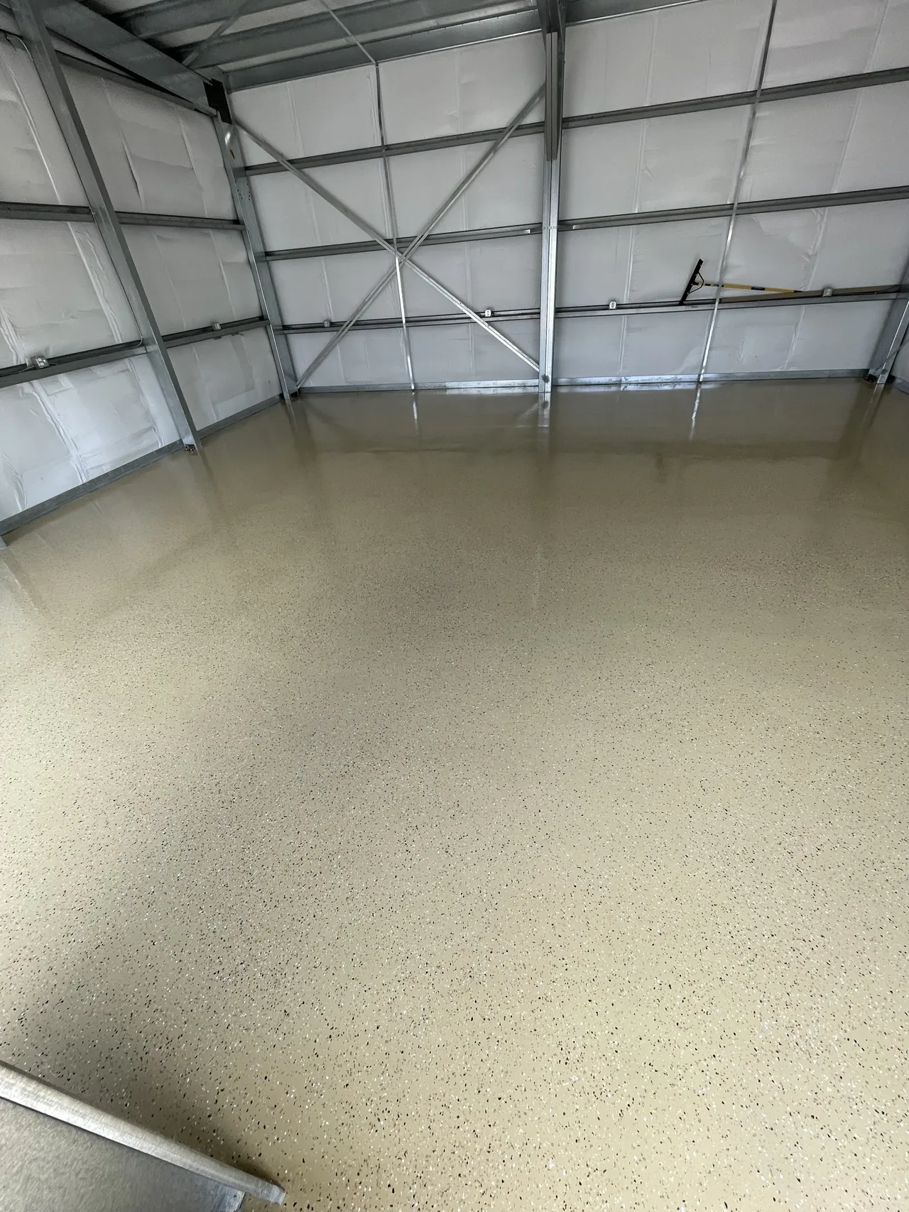 Tan flake floor beside the wall of a metal-framed shop