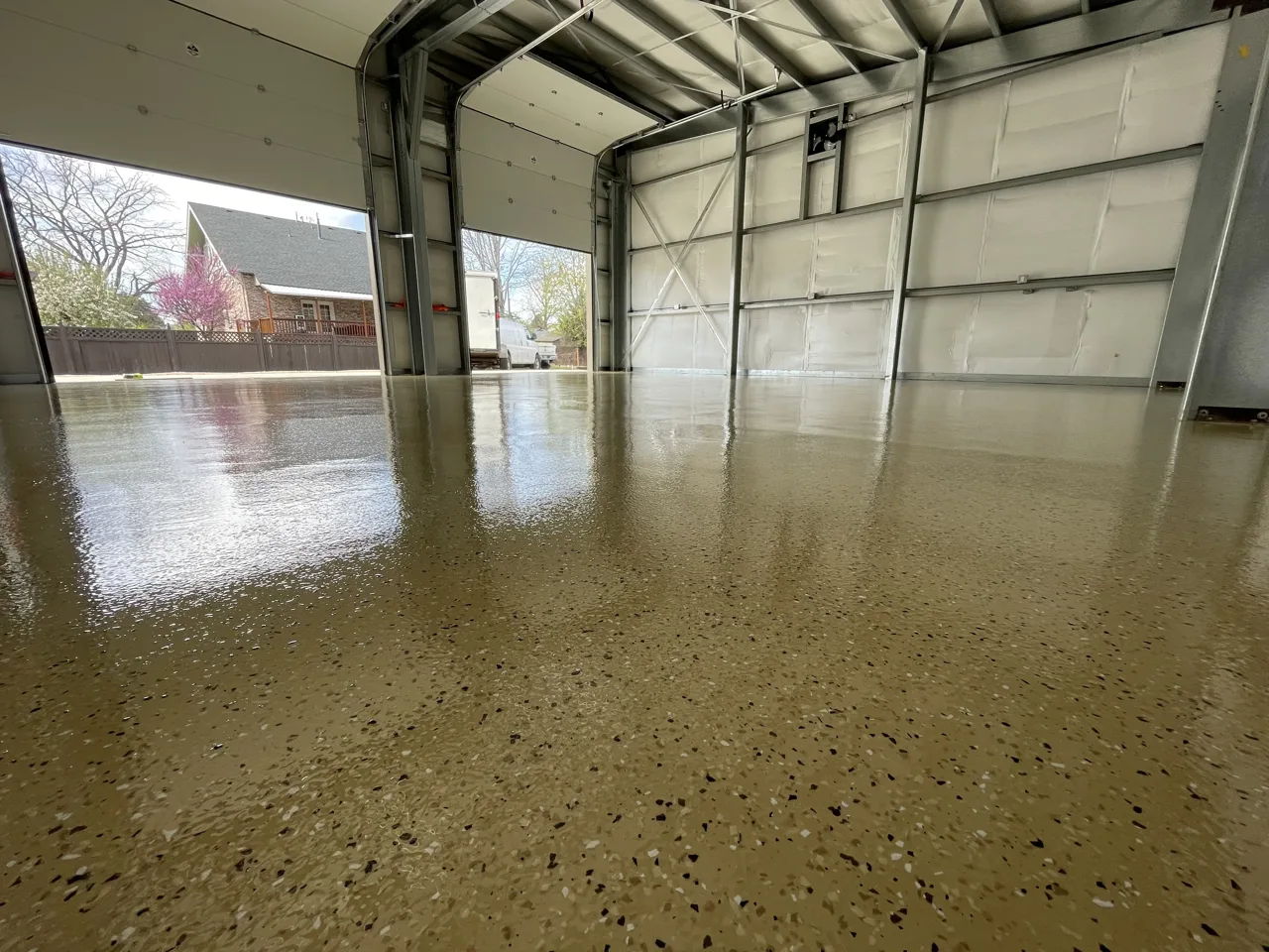 Tan flake shop floor beside metal walls and a large overhead door