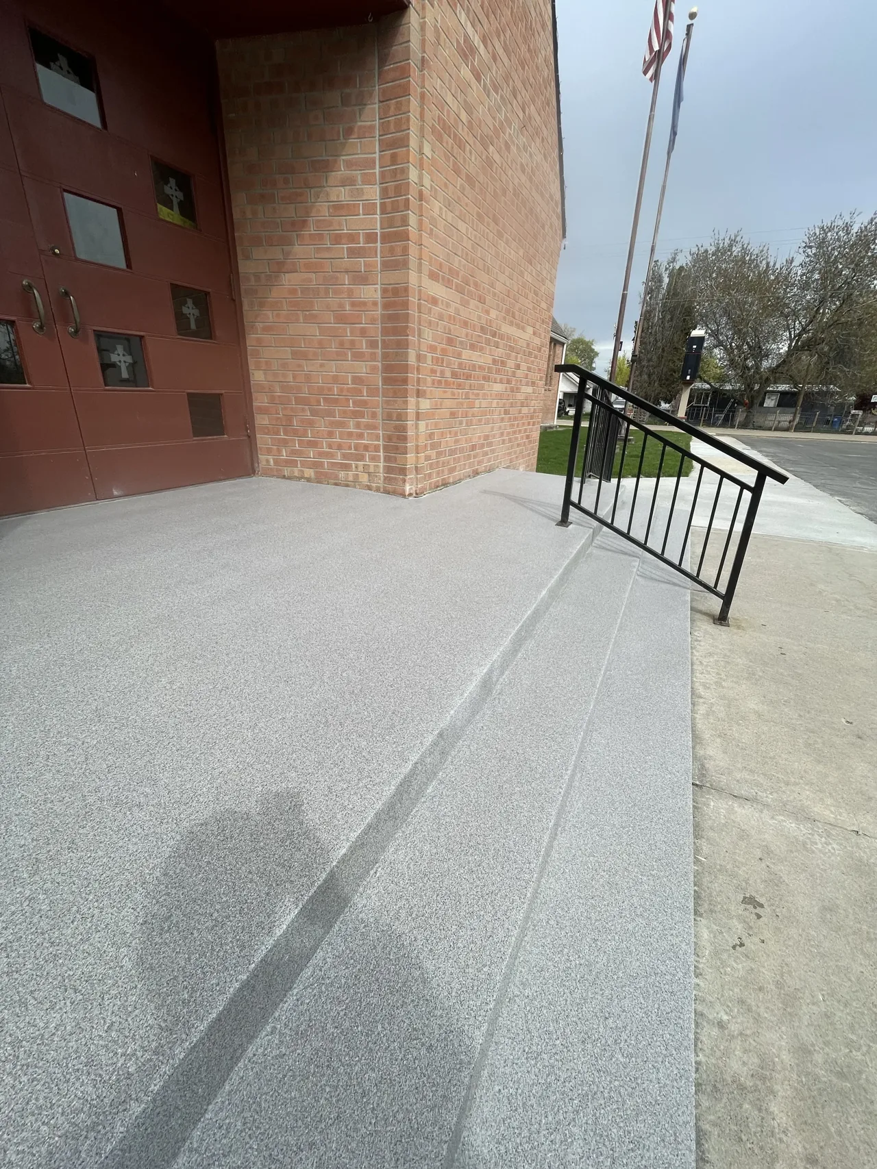 Gray decorative coating on entrance steps beside a brick wall